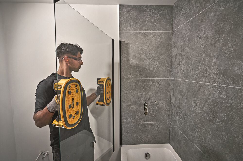 User carrying large shower glass panel with DEWALT 20V MAX Grabo Lifters