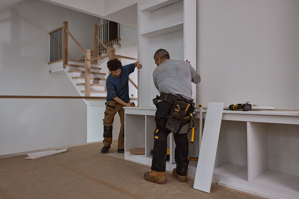 Two carpenters fit a custom cabinet
