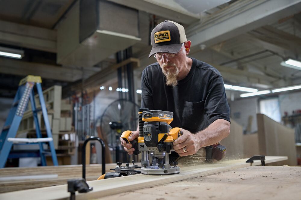 A carpenter uses a router in the woodshop