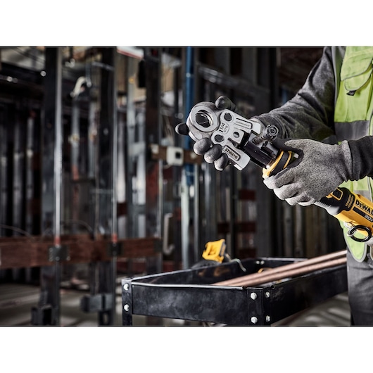 Tradesman is switching the jaw on the DEWALT Compact Press Tool in a mechanical room.